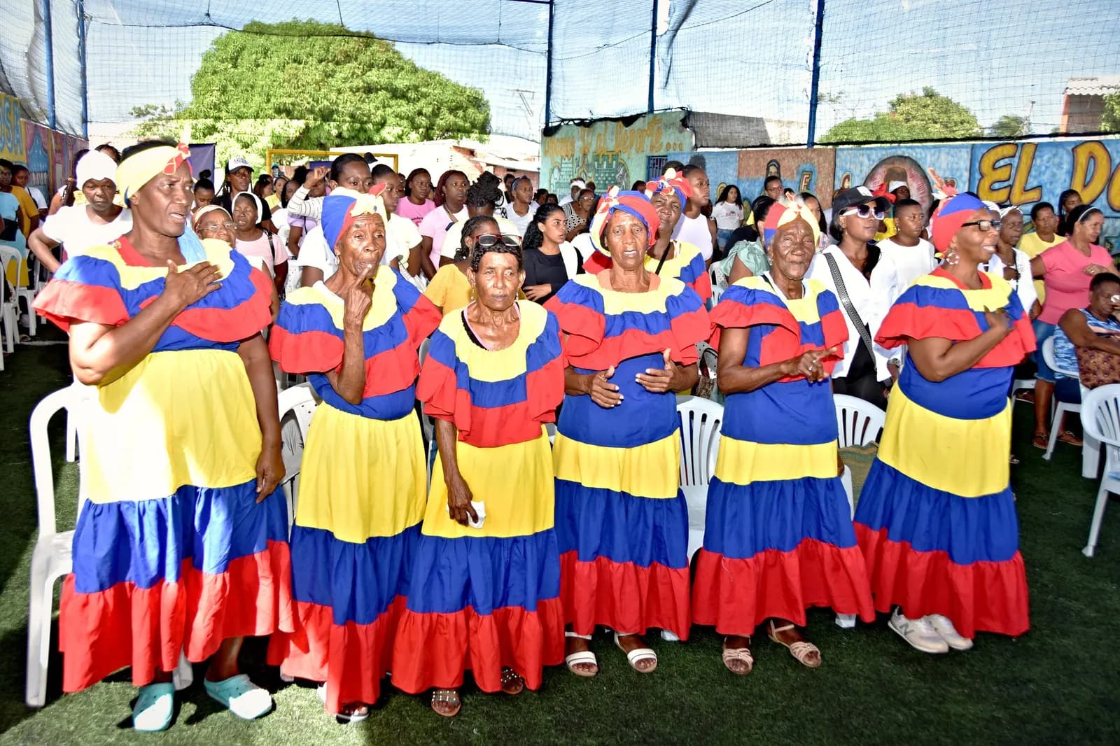 Mujeres palenqueras con vestidos tricolor, con la mano en el pecho, en un encuentro de fin de año
