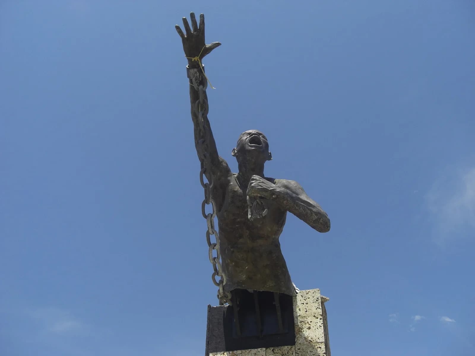 Estatua de Benkos Biohó en la plaza de San Basilio de Palenque: un hombre rompe sus cadenas con el brazo en alto