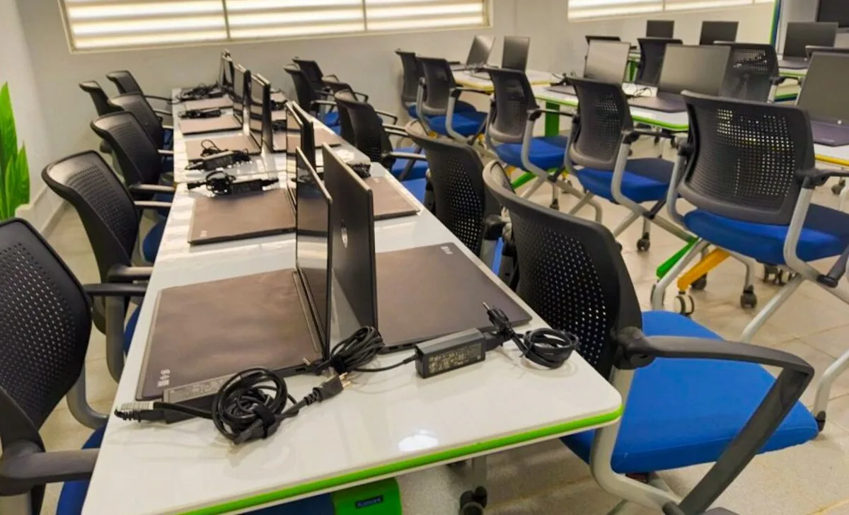 Aula del Centro de Innovación Tecnológica Orika: filas de mesas blancas con computadores portátiles y sillas azules